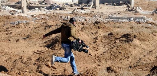 Syrský kameraman běží ve zpustošené oblasti západně od Damašku.